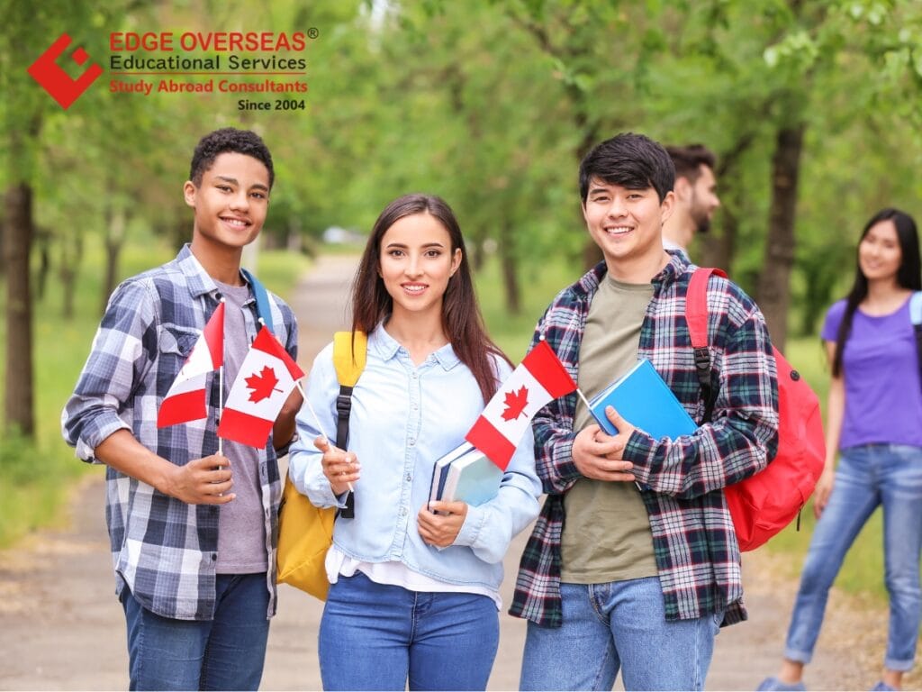 Group of international students holding Canadian flags and books on a campus walkway, smiling, representing Canada study visa applicants.
